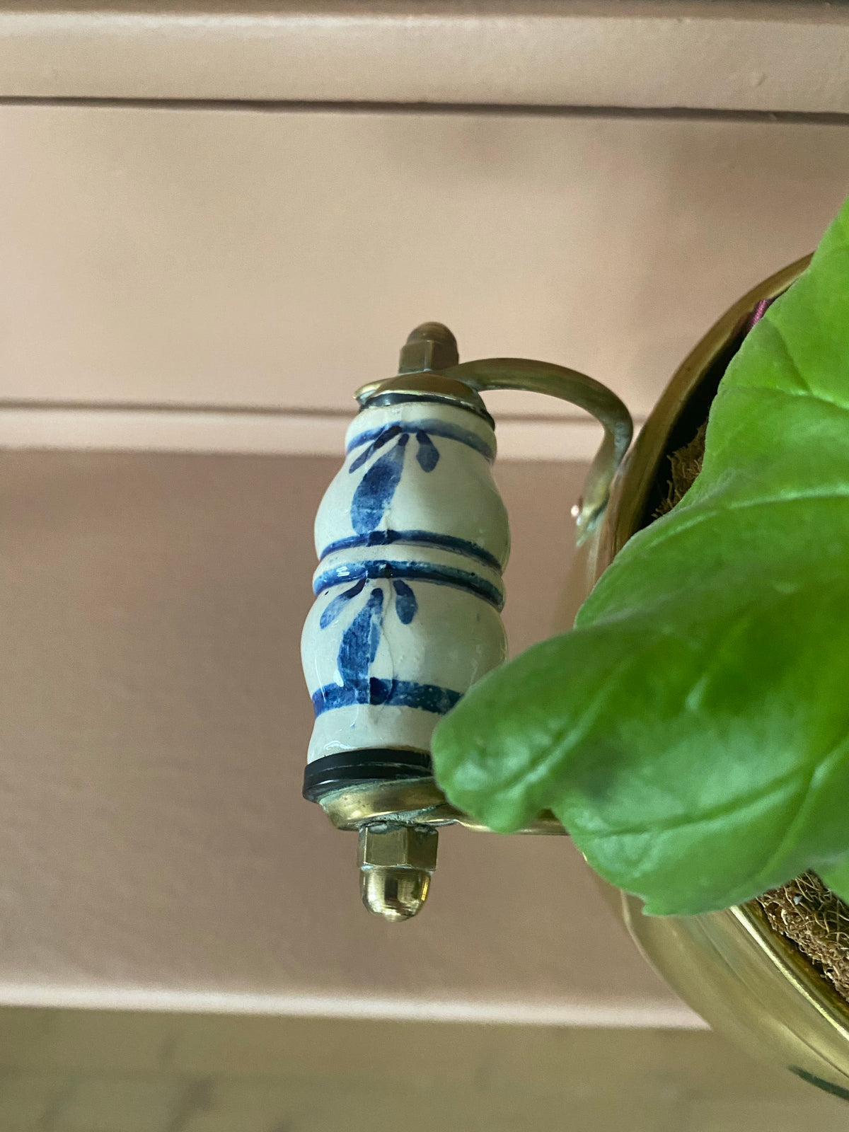 Mässingskruka på fot med handtag i blåvitt porslin