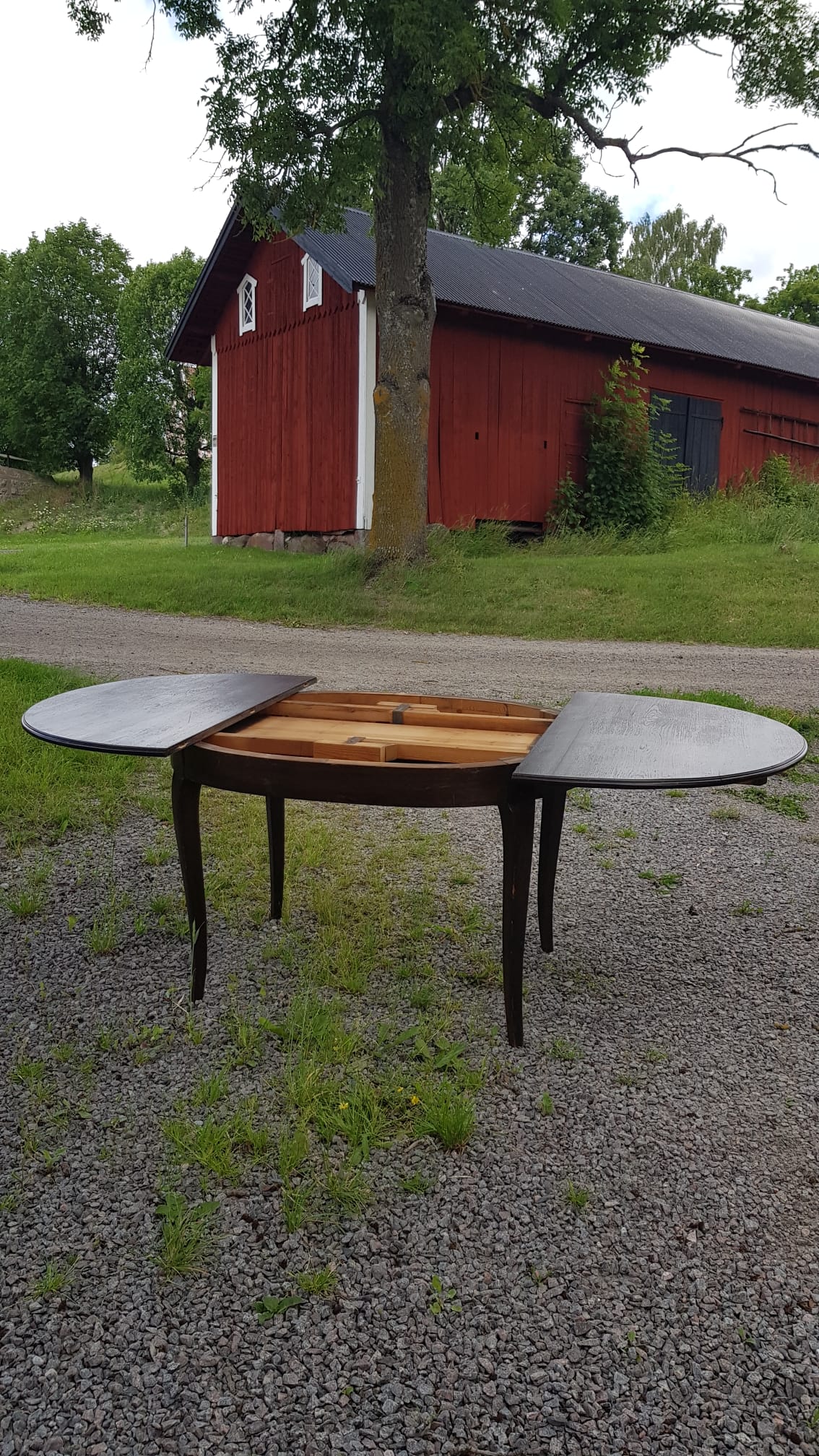 Ovalt matbord i mörkt trä med iläggsskivor