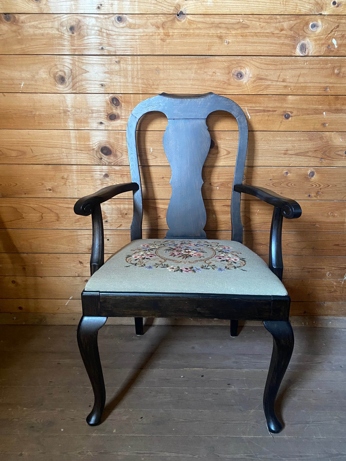 Stor karmstol i mörkt trä med broderad sits