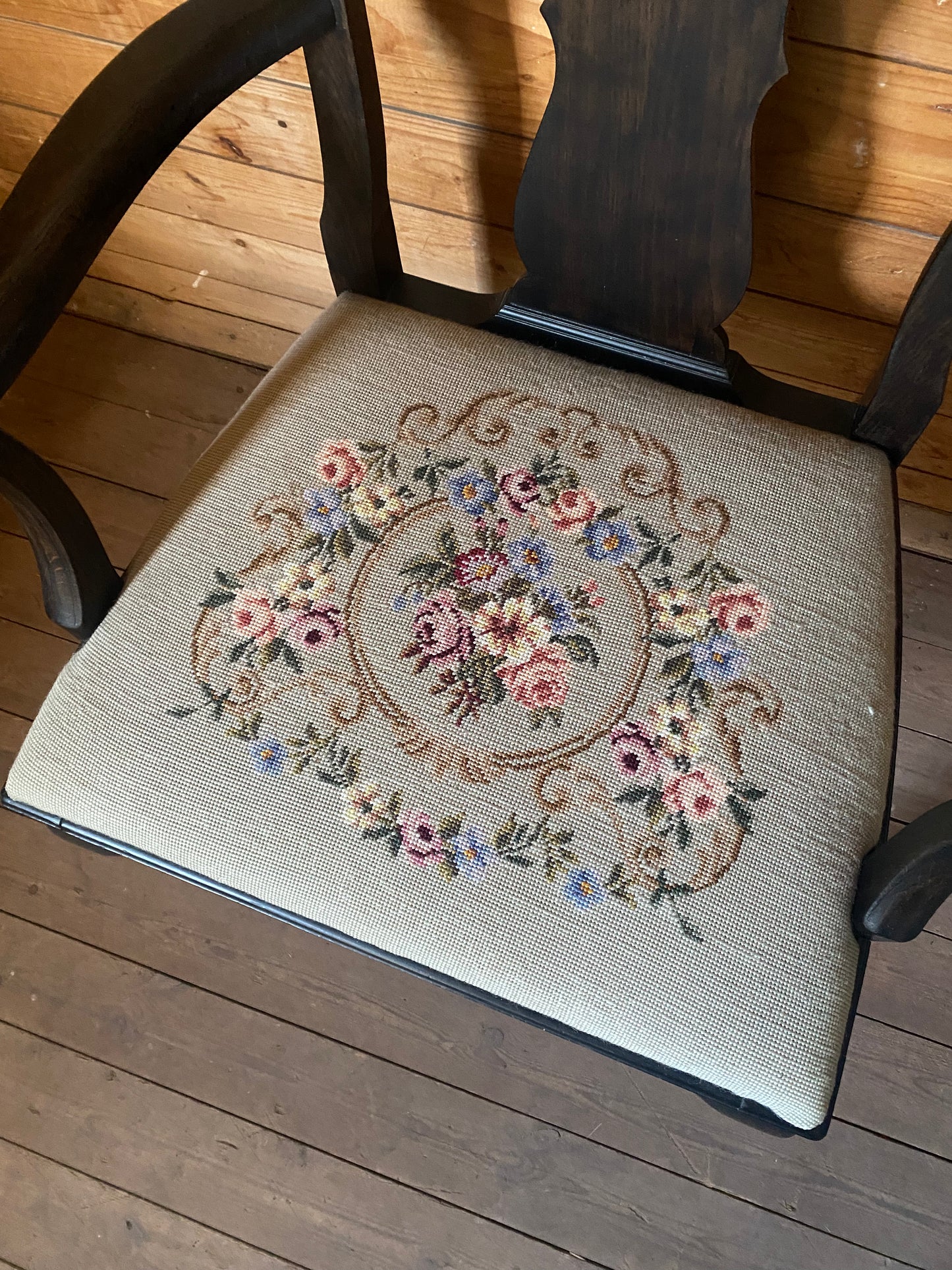 Stor karmstol i mörkt trä med broderad sits