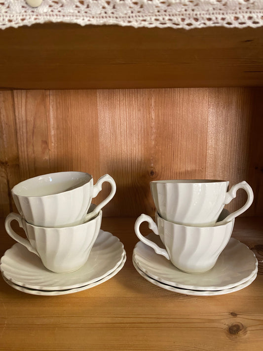 Fyra vita kaffekoppar med fat