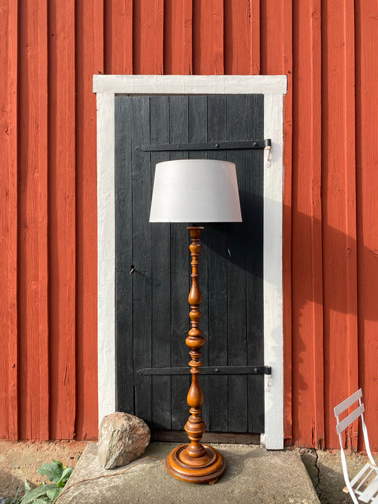 Golvlampa med svarvad fot i mörkt trä