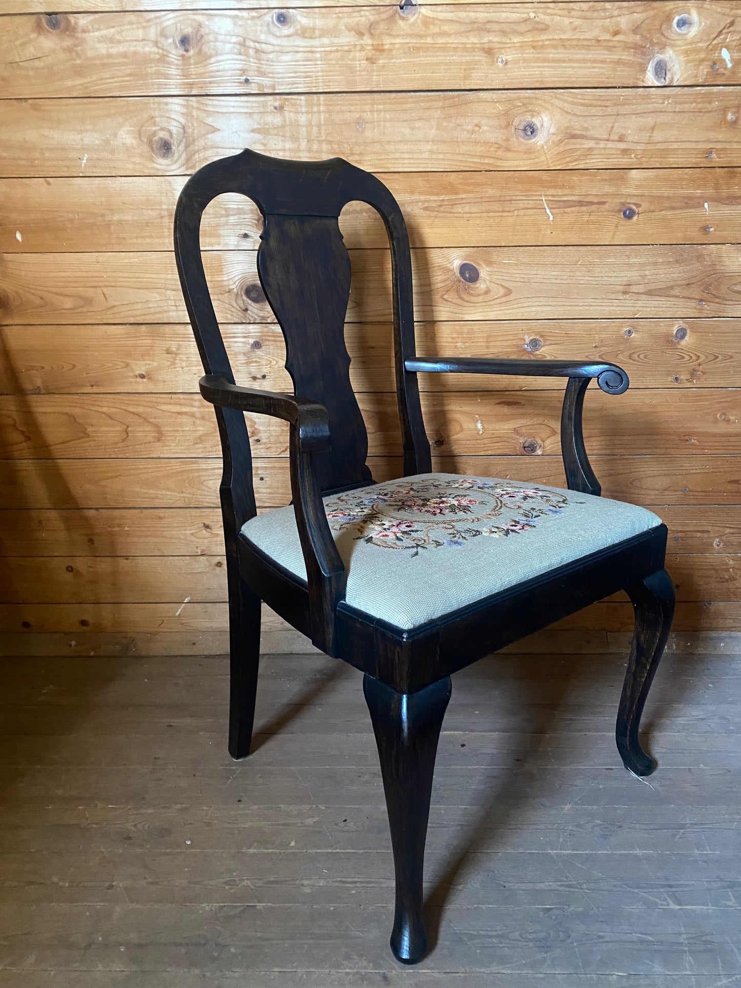 Stor karmstol i mörkt trä med broderad sits